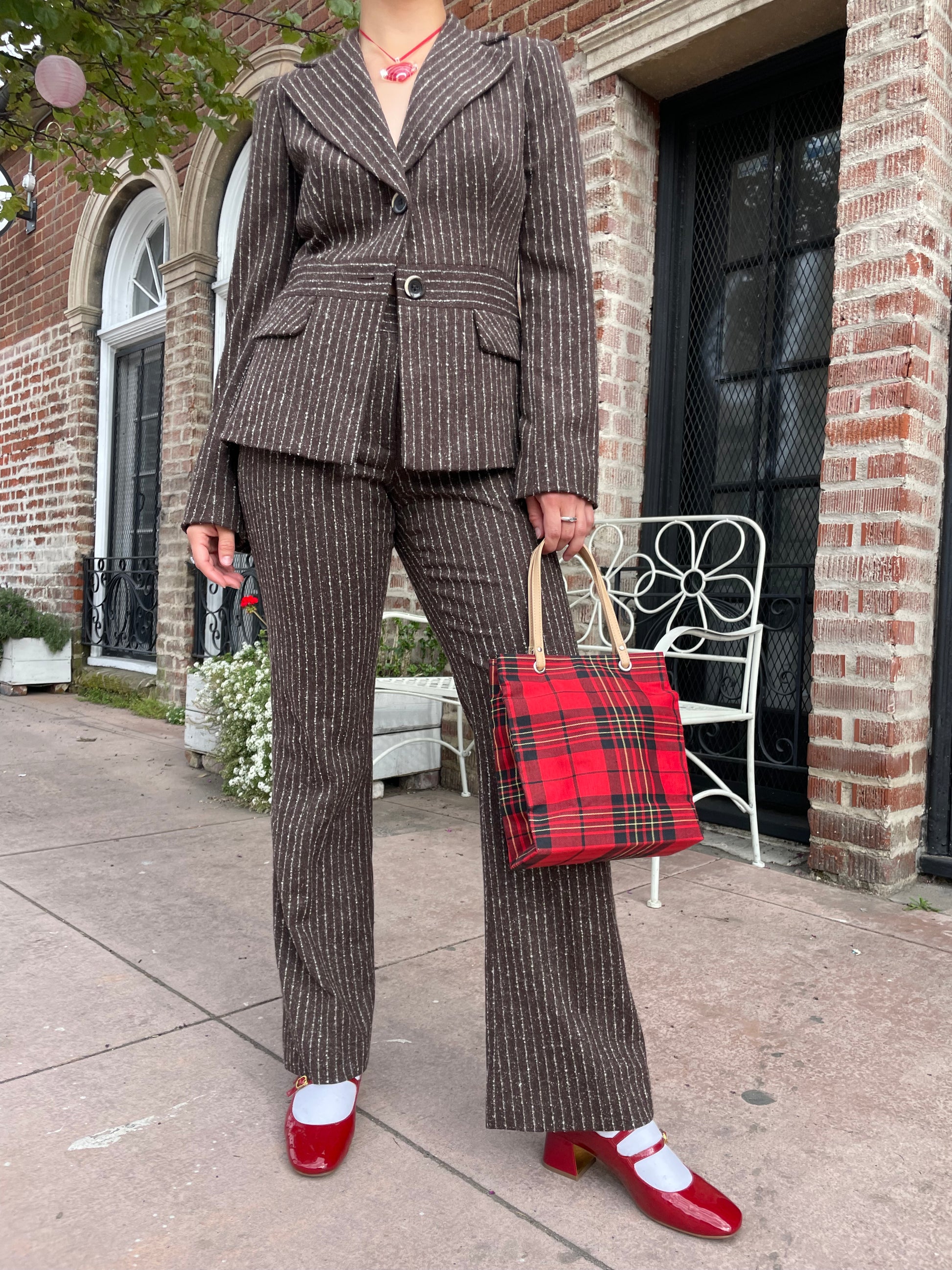 girl wearing brown blazer and slacks set with red plaid purse