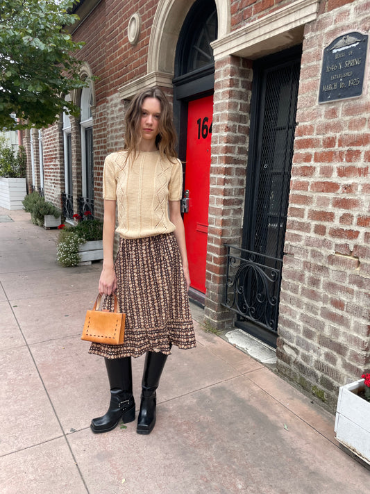 girl wearing cream sweater and brown floral skirt