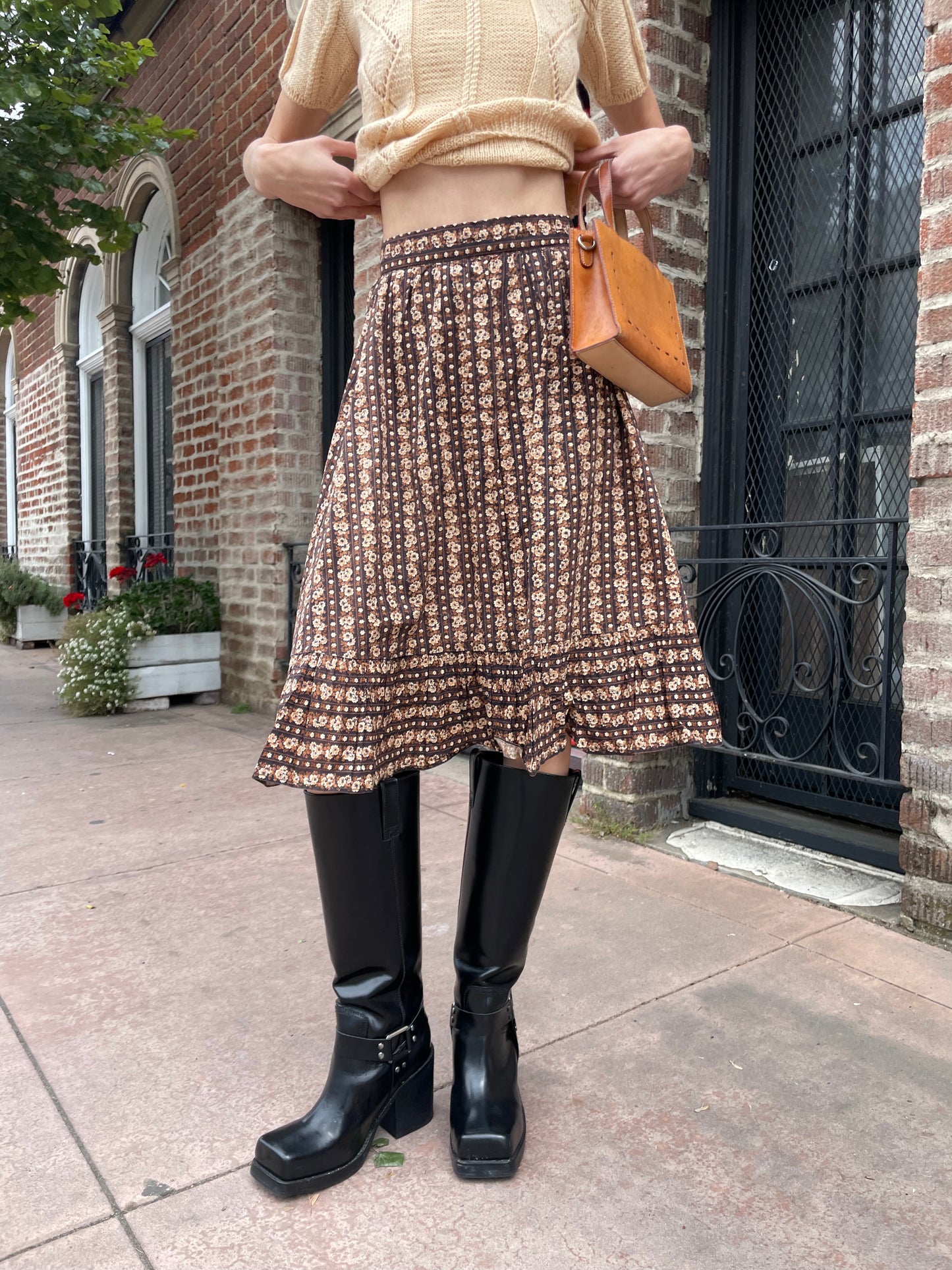 girl wearing cream sweater and brown floral skirt