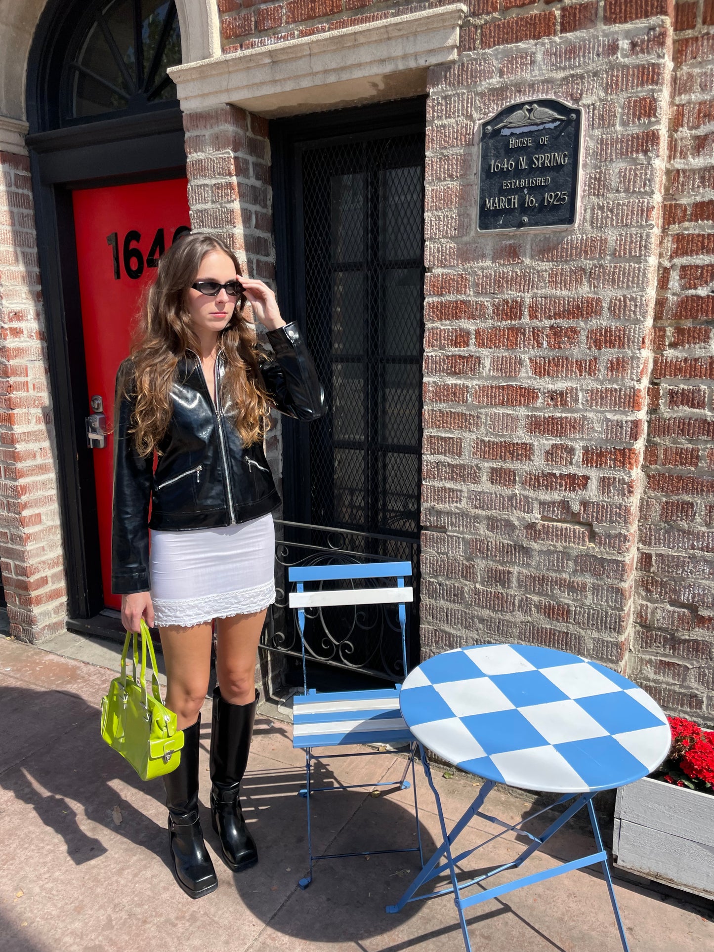 girl wearing black leather jacket and white skirt and tall black boots