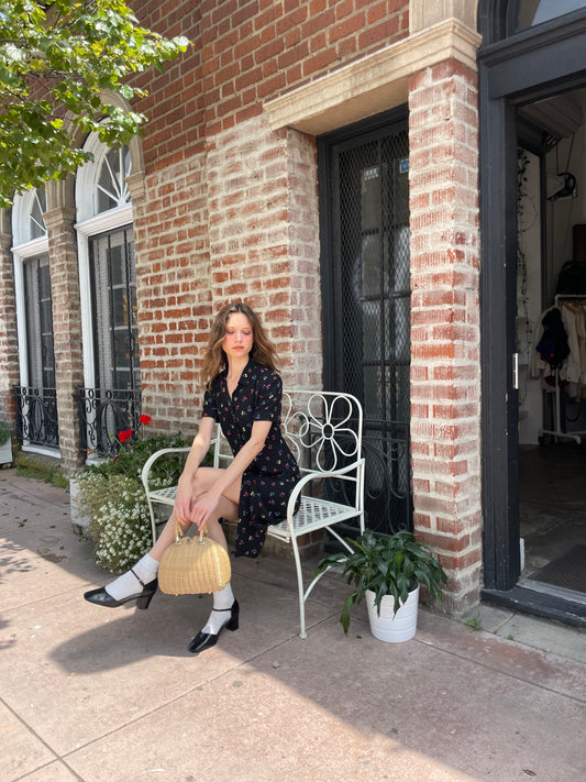 girl sitting wearing black floral print dress