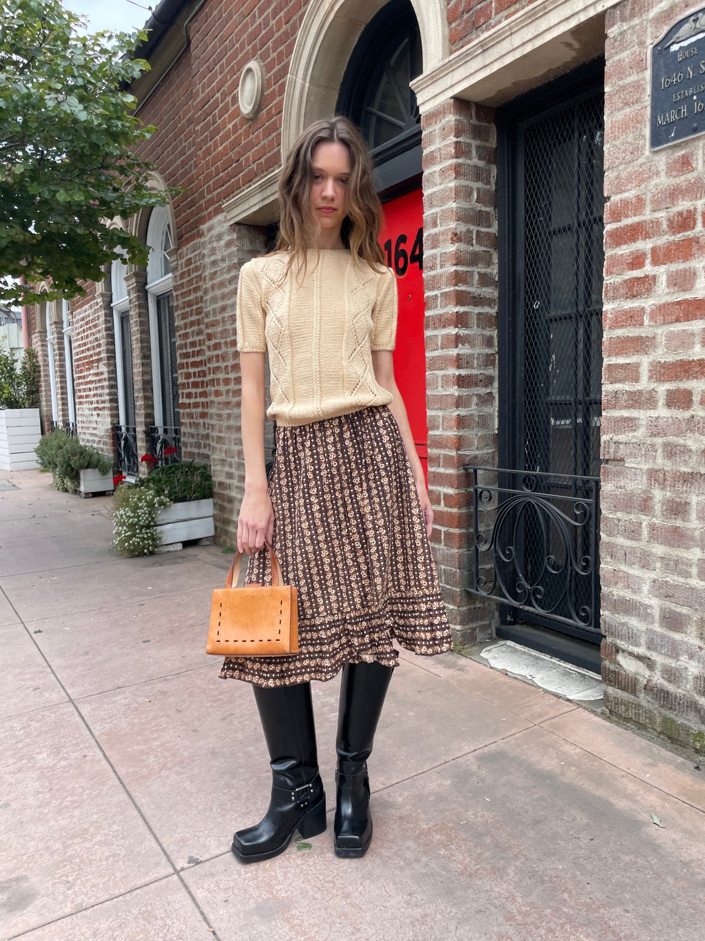 girl wearing cream sweater and brown floral skirt