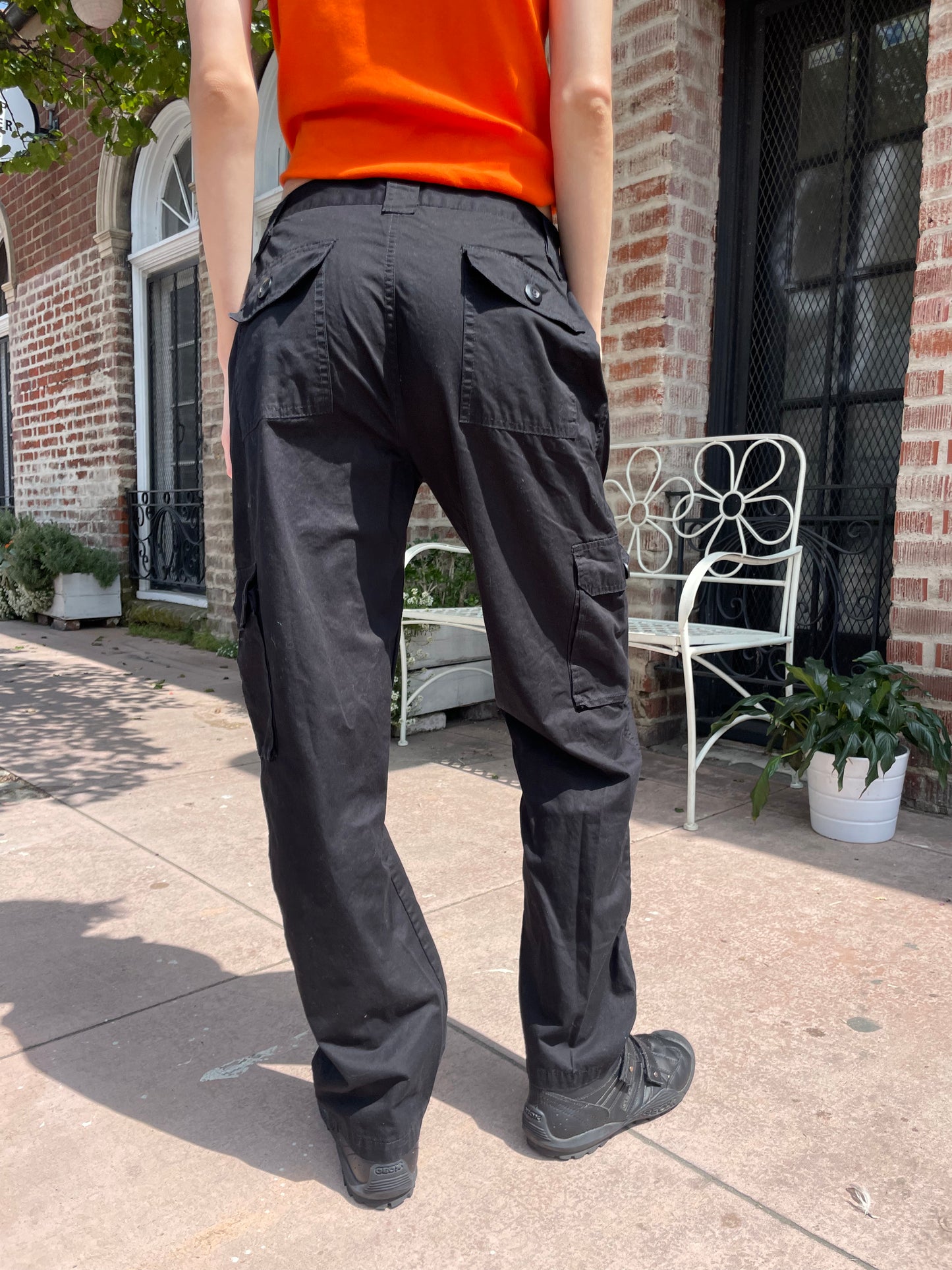 bottom half of girl wearing orange tank top black cargo pants