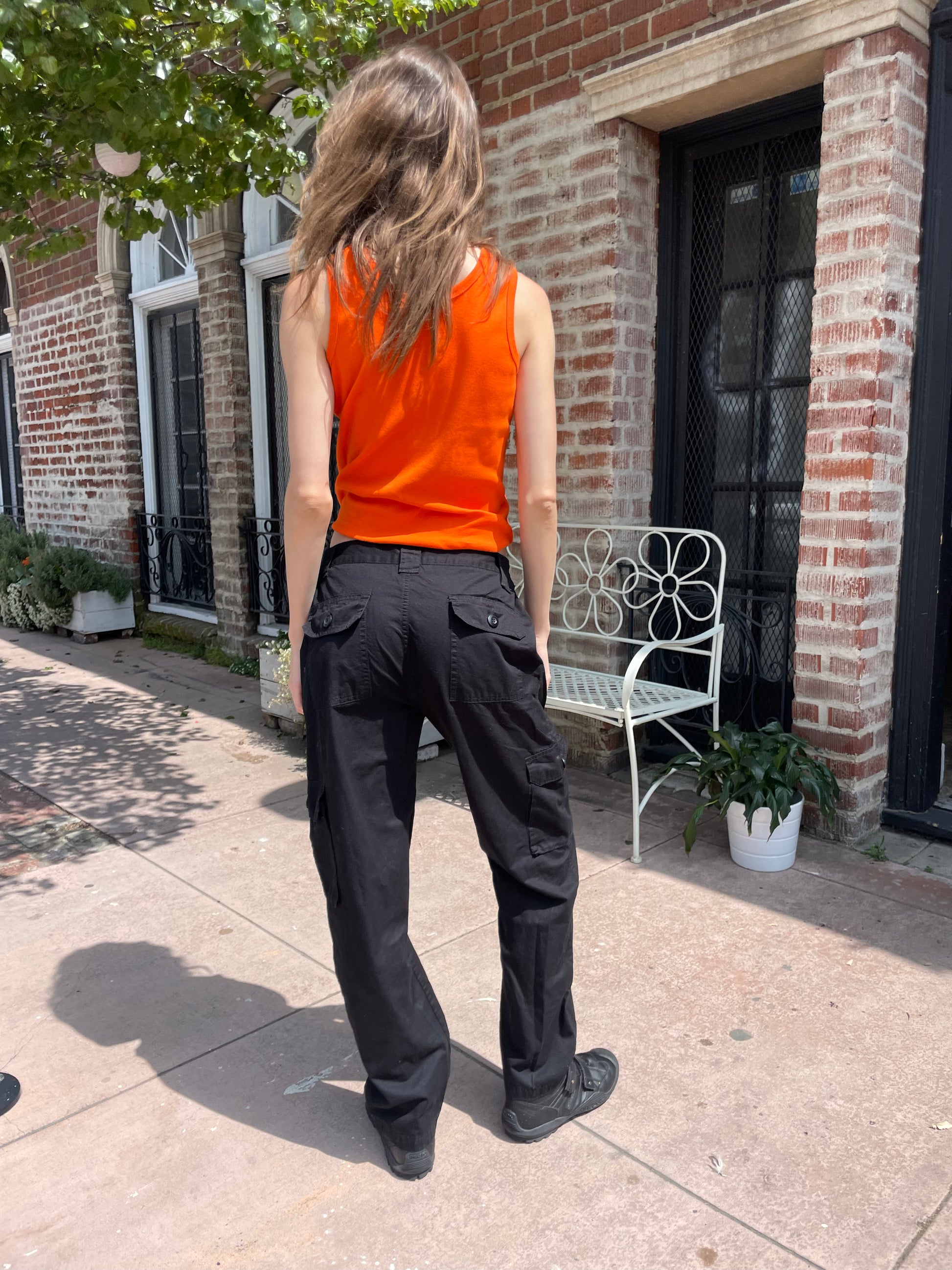 back of girl wearing orange tank top black cargo pants