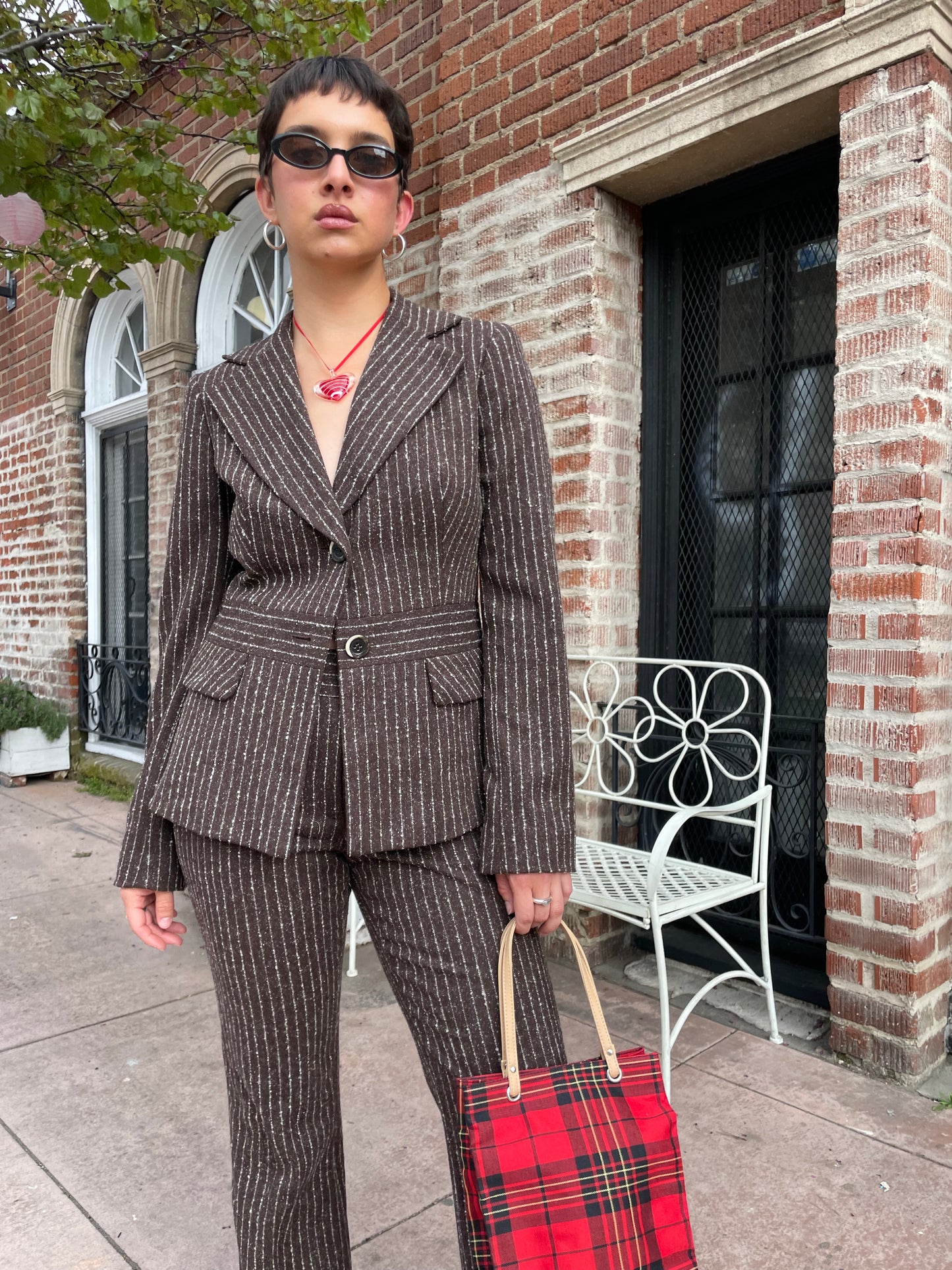 girl wearing brown blazer and slacks set with red plaid purse