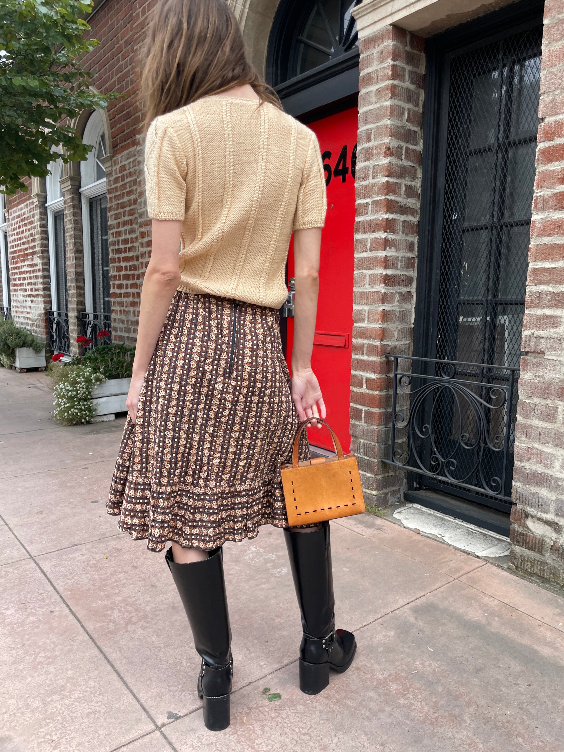 girl wearing cream sweater and brown floral skirt