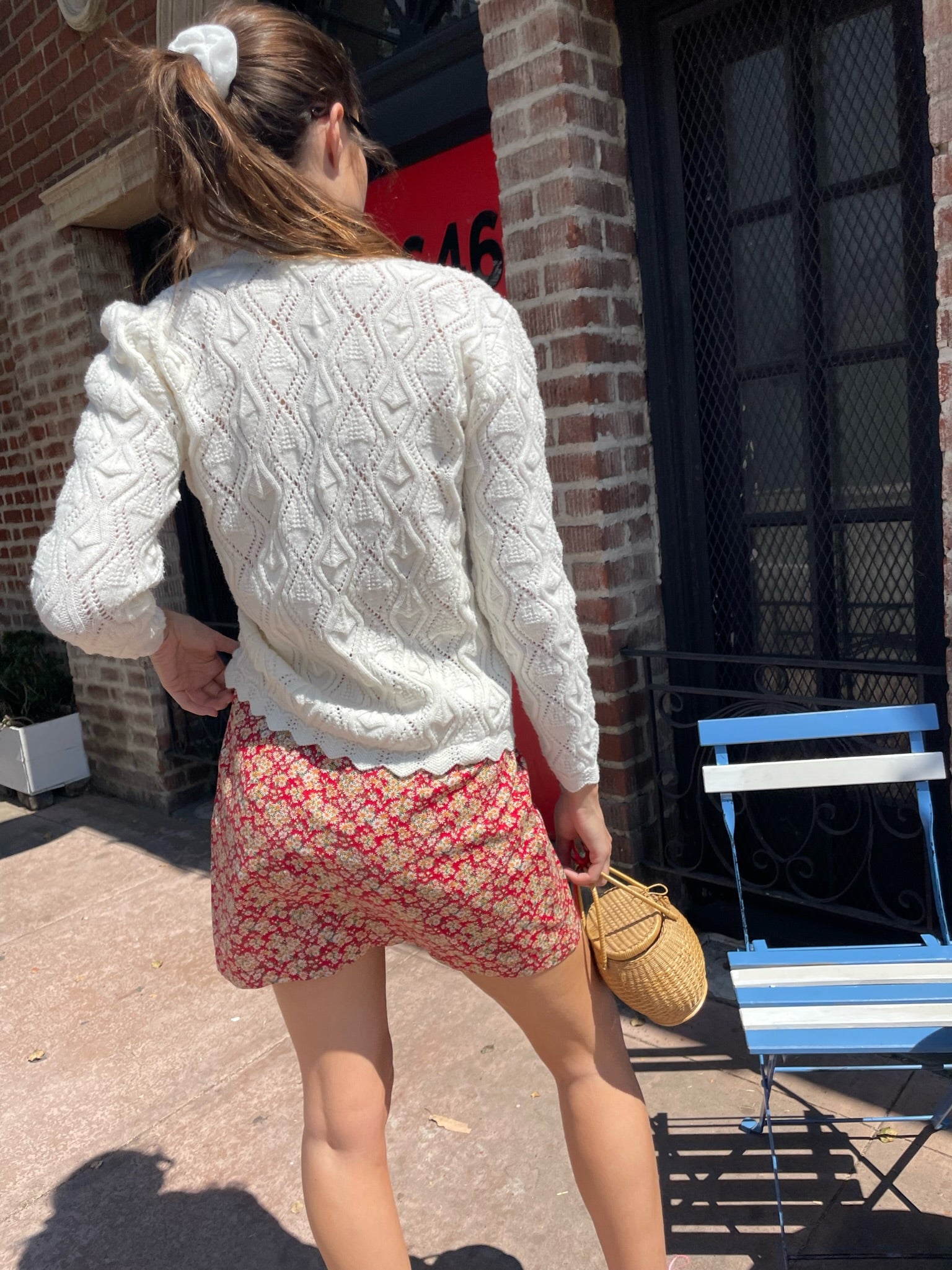 girl wearing red floral skirt and white cardigan