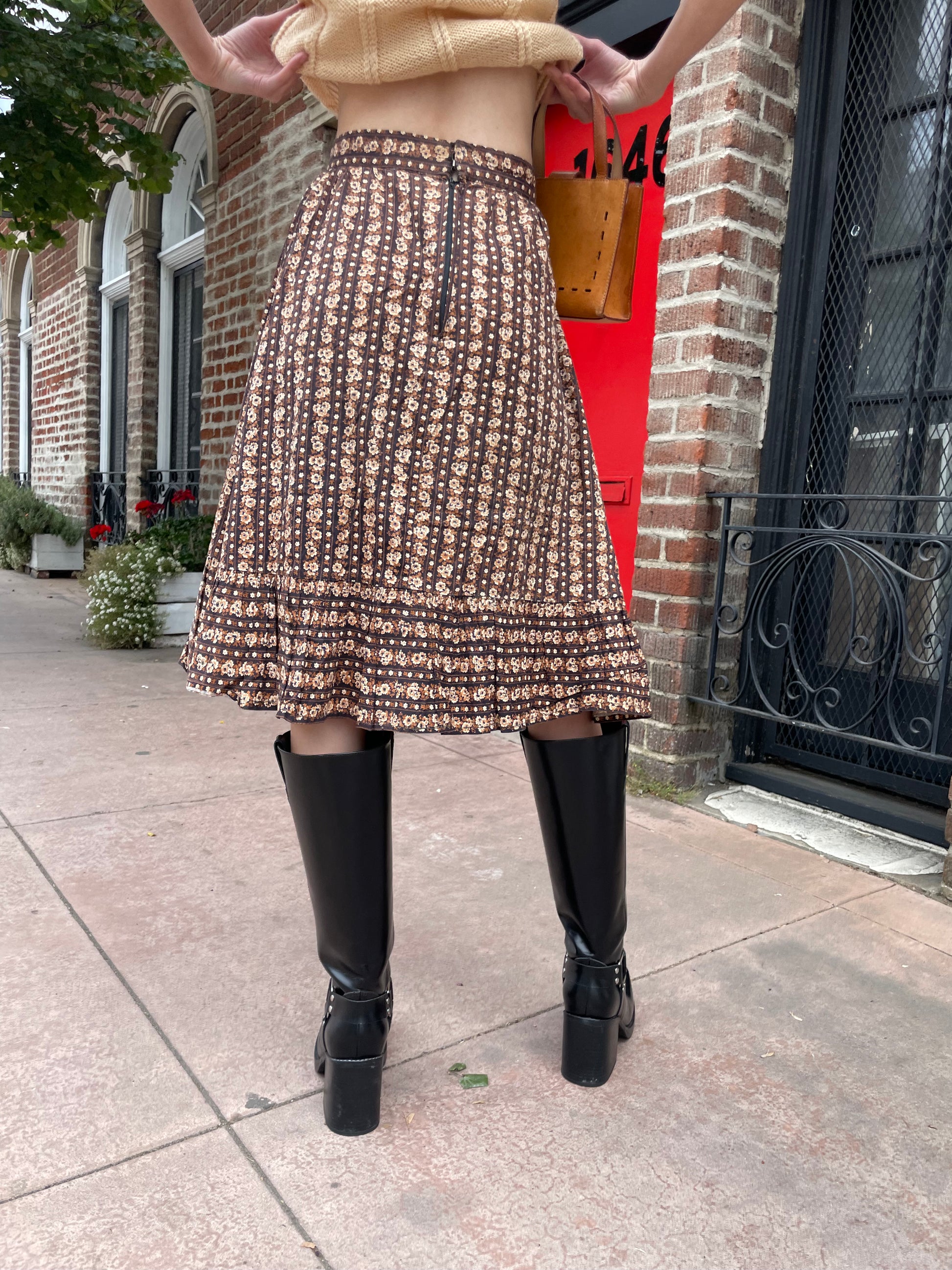 girl wearing cream sweater and brown floral skirt