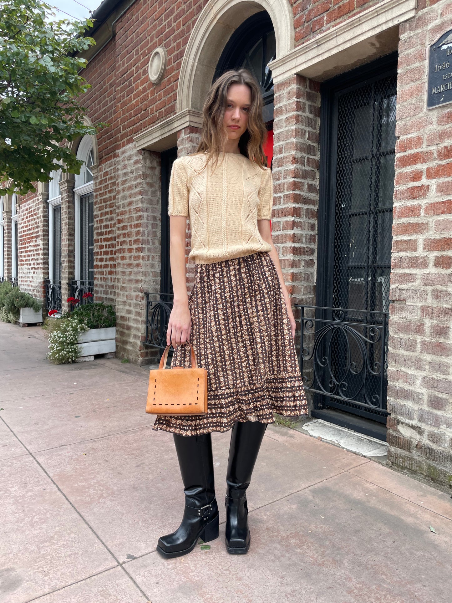 girl wearing cream sweater and brown floral skirt