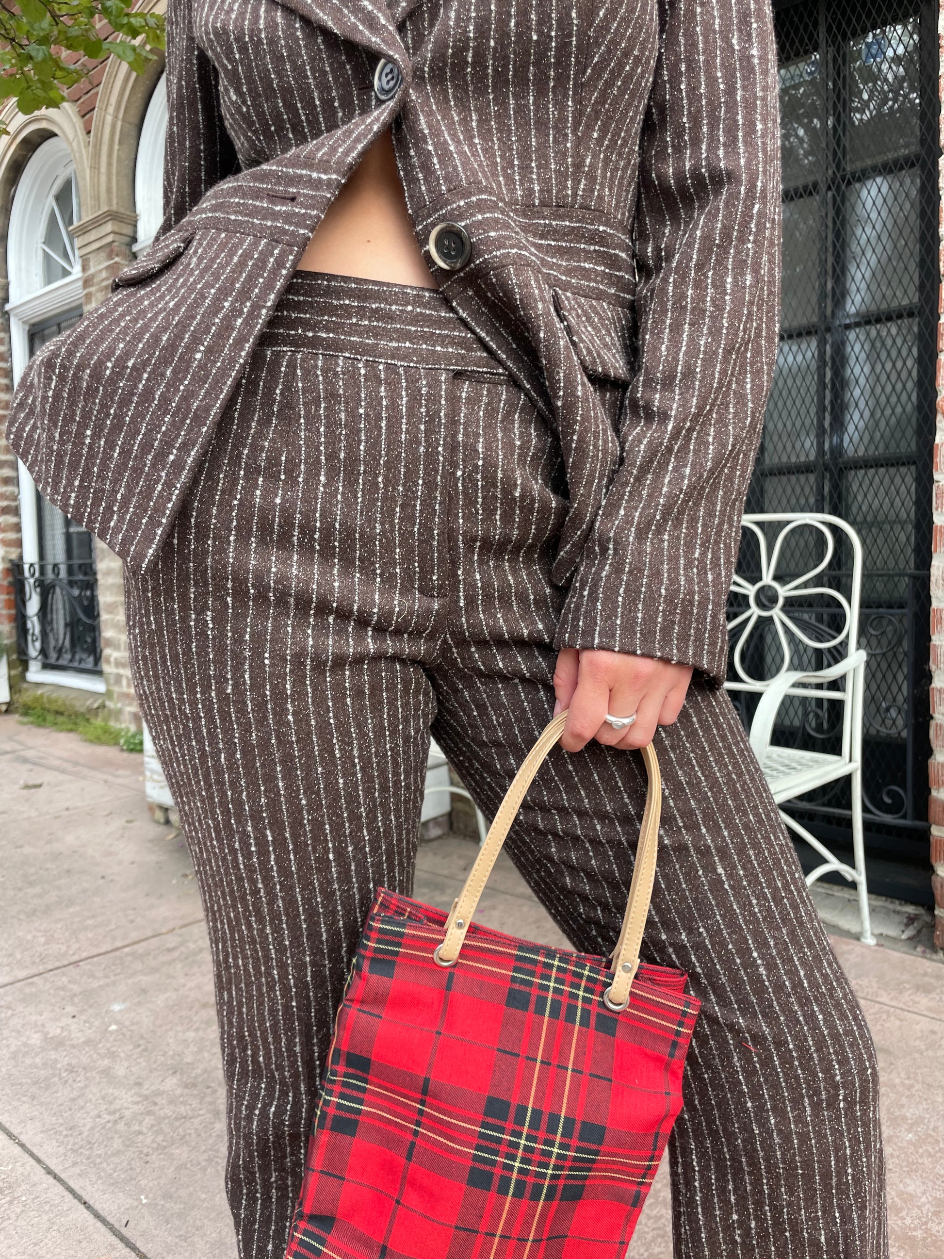 girl wearing brown blazer and slacks set with red plaid purse