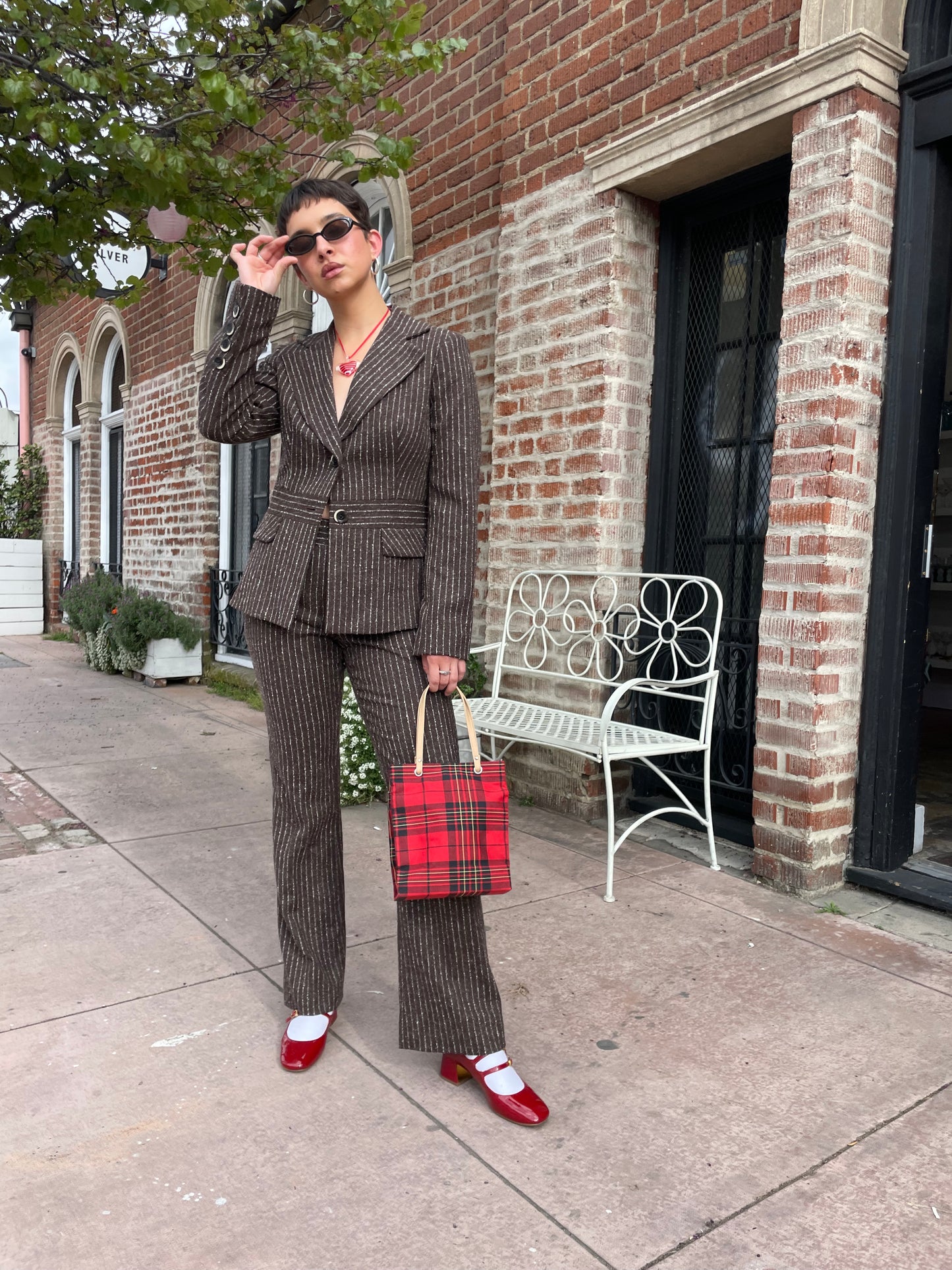 girl wearing brown blazer and slacks set with red plaid purse