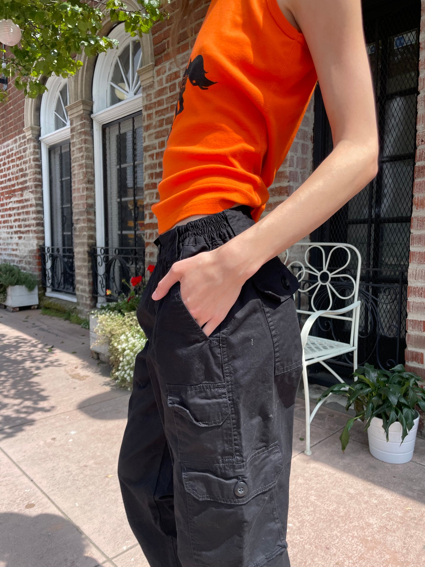 girl wearing orange tank top black cargo pants and black sunglasses