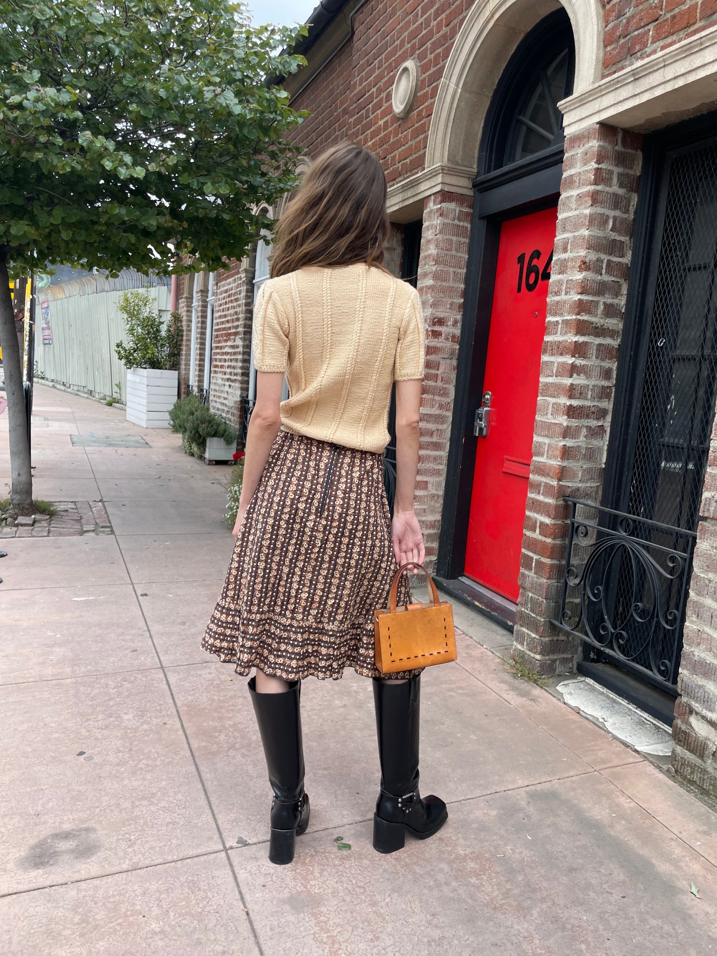 girl wearing cream sweater and brown floral skirt