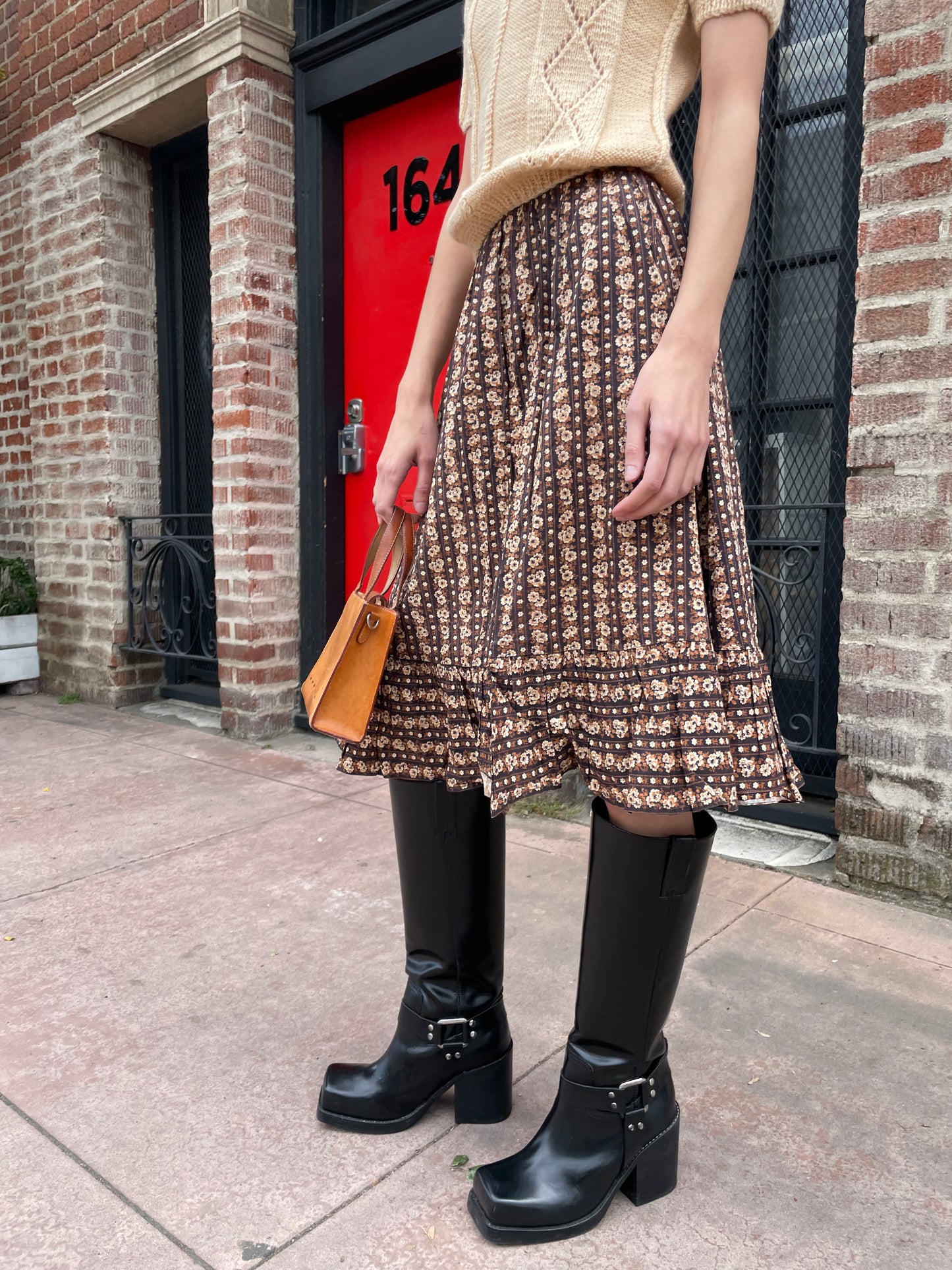 girl wearing cream sweater and brown floral skirt