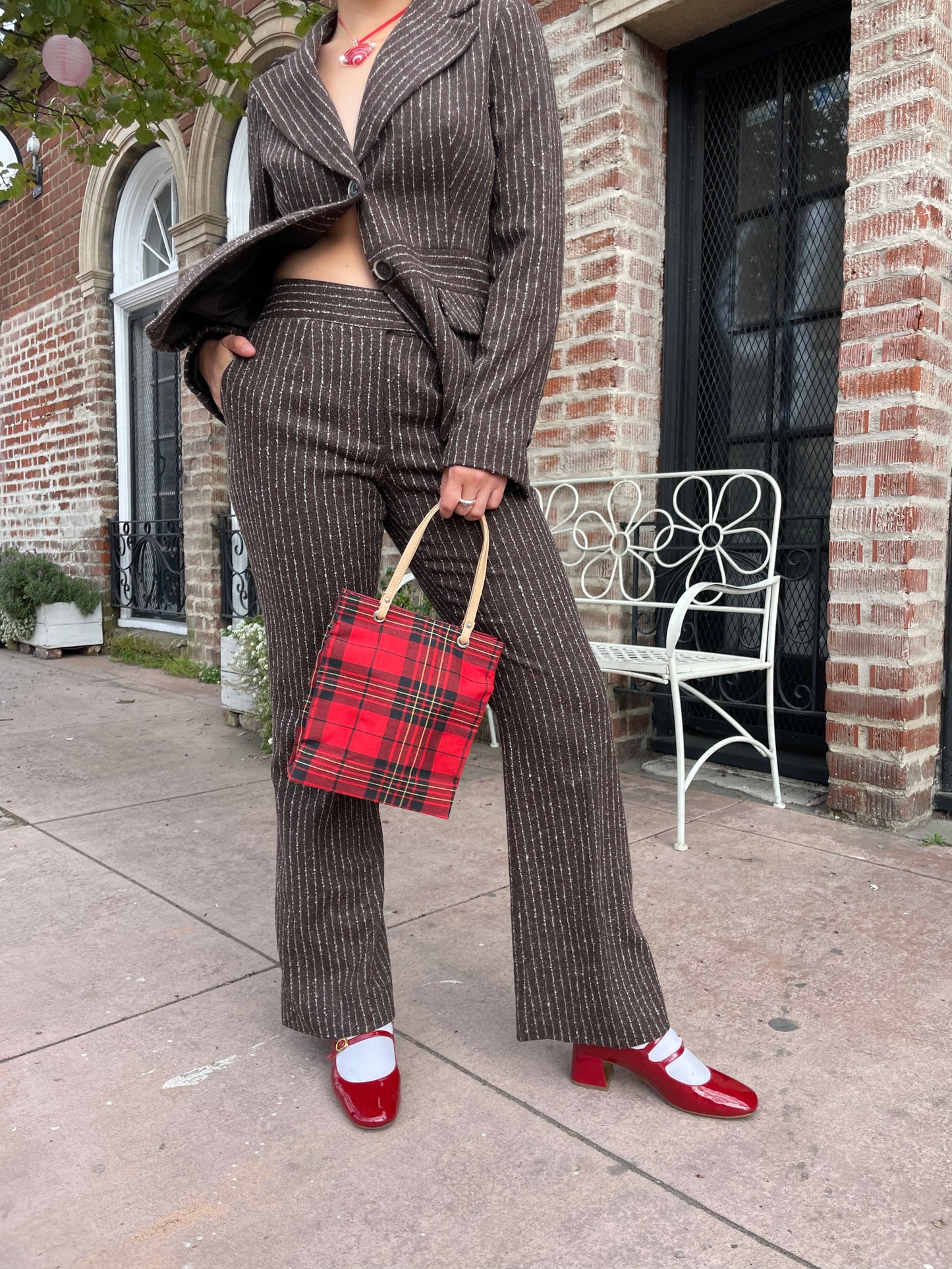 girl wearing brown blazer and slacks set with red plaid purse