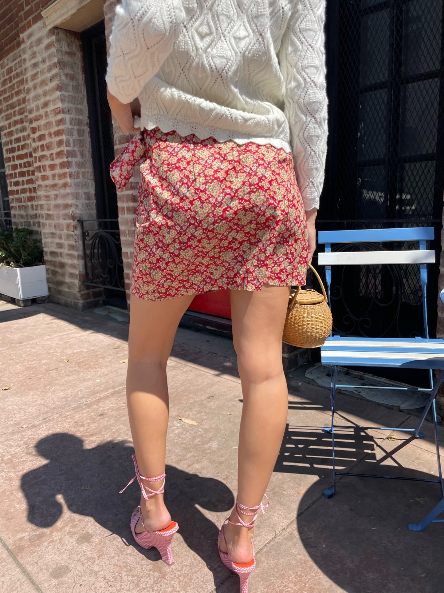 girl wearing red floral skirt and white cardigan