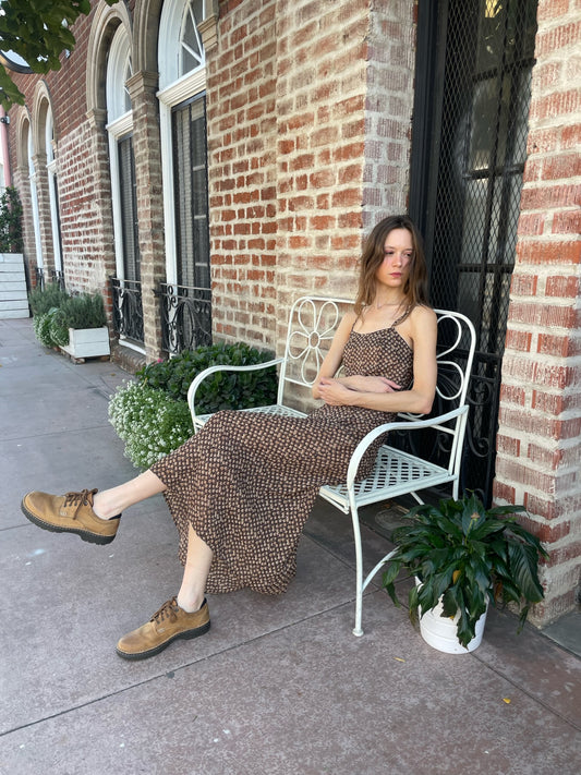 girl sitting wearing brown dress and brown shoes