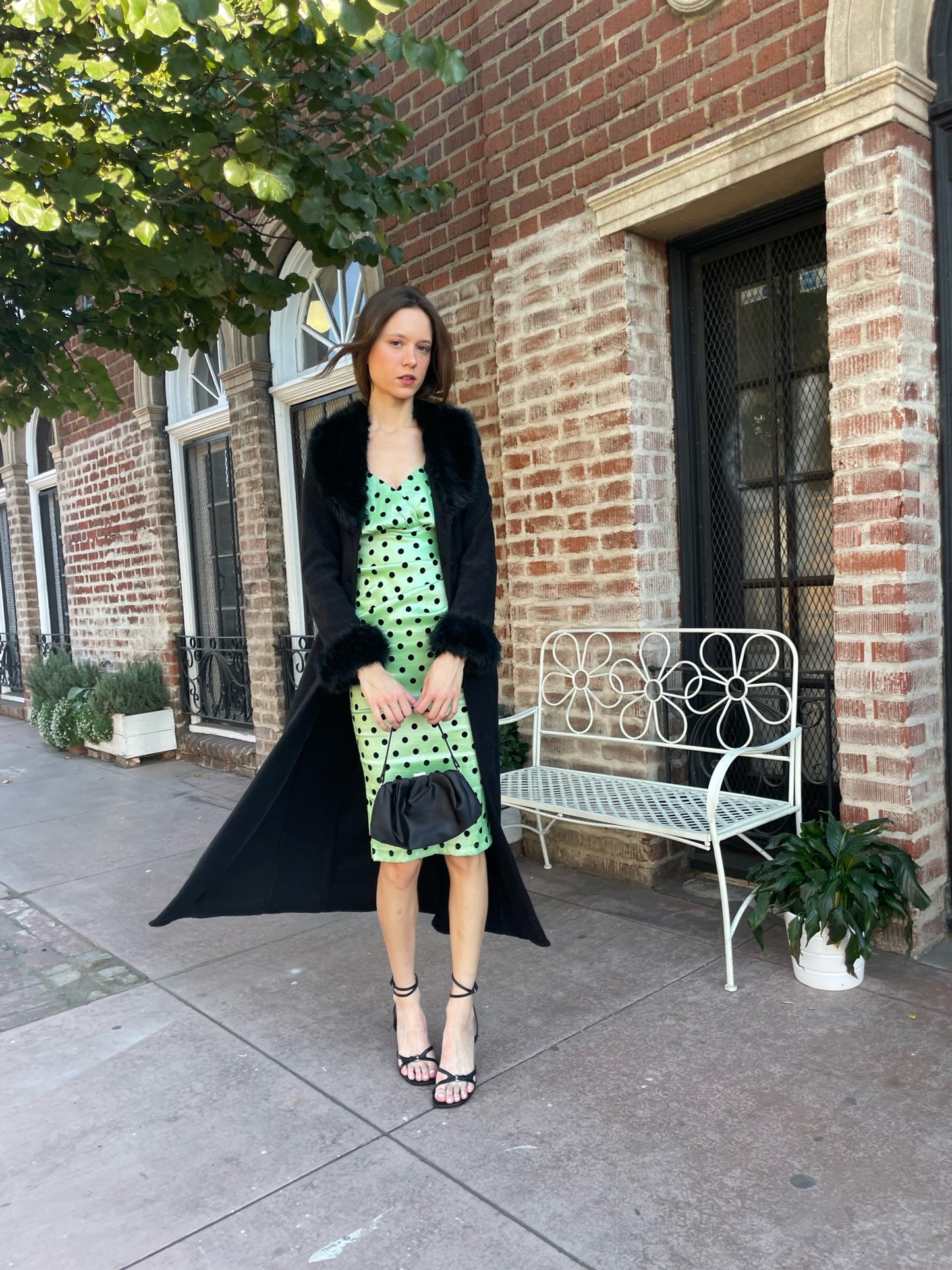 girl wearing a black fur collar coat with green polka dot dress