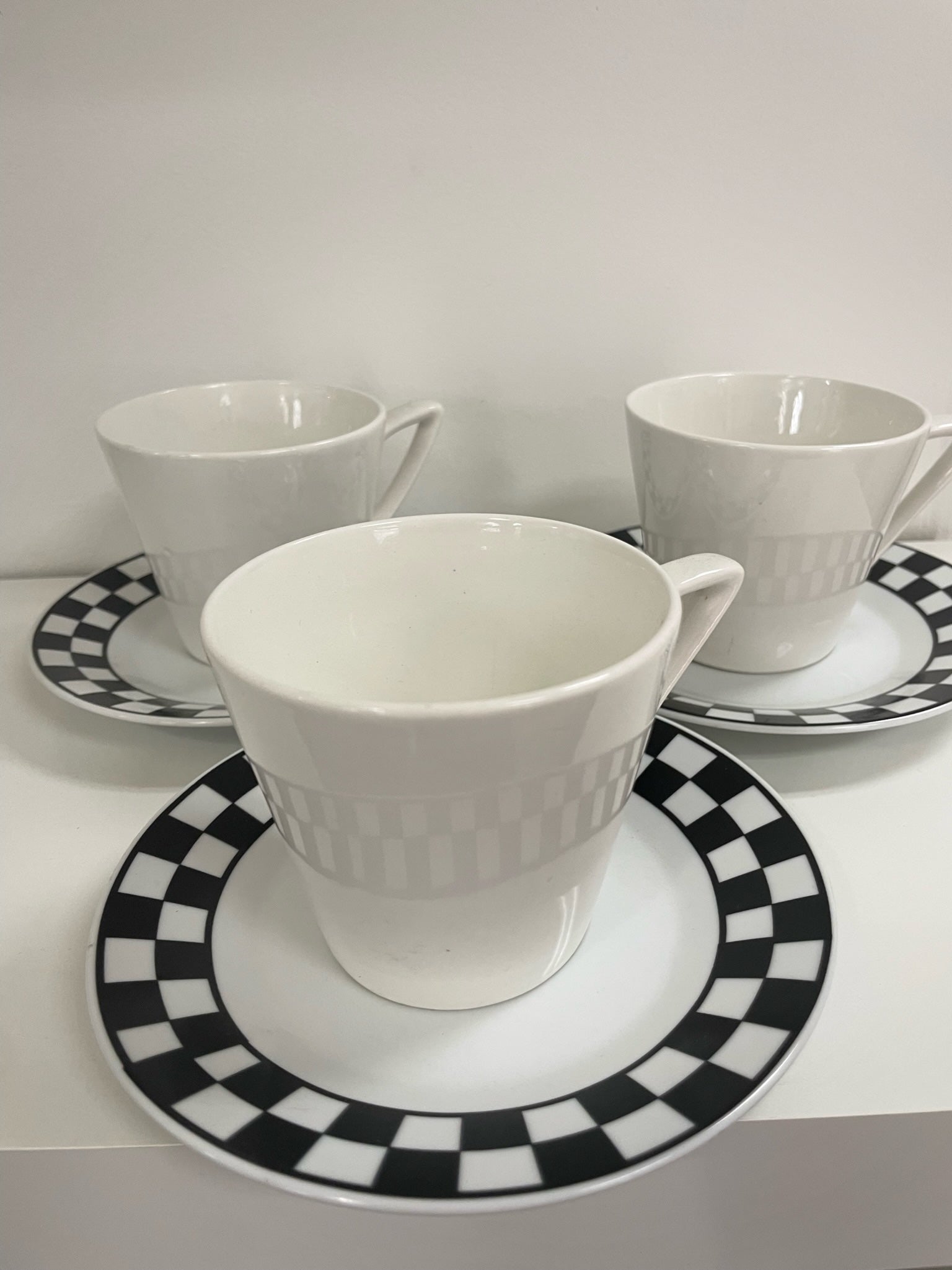 three coffee cups and saucers with black and white checker detail