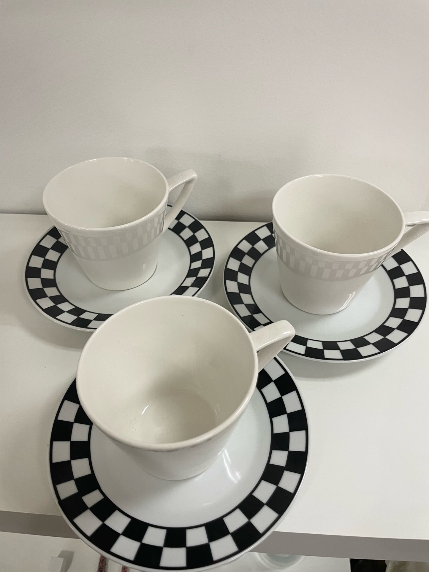 three coffee cups and saucers with black and white checker detail