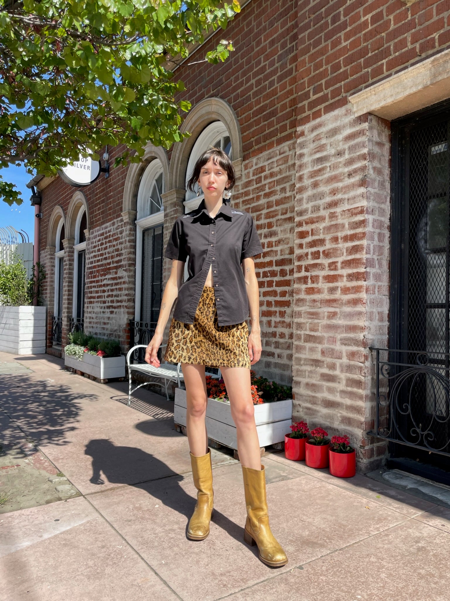 girl wearing a black button up shirt and leather mini skirt and brown boots