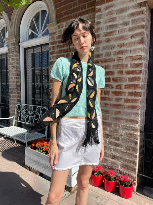 girl wearing blue top, white denim skirt and black scarf