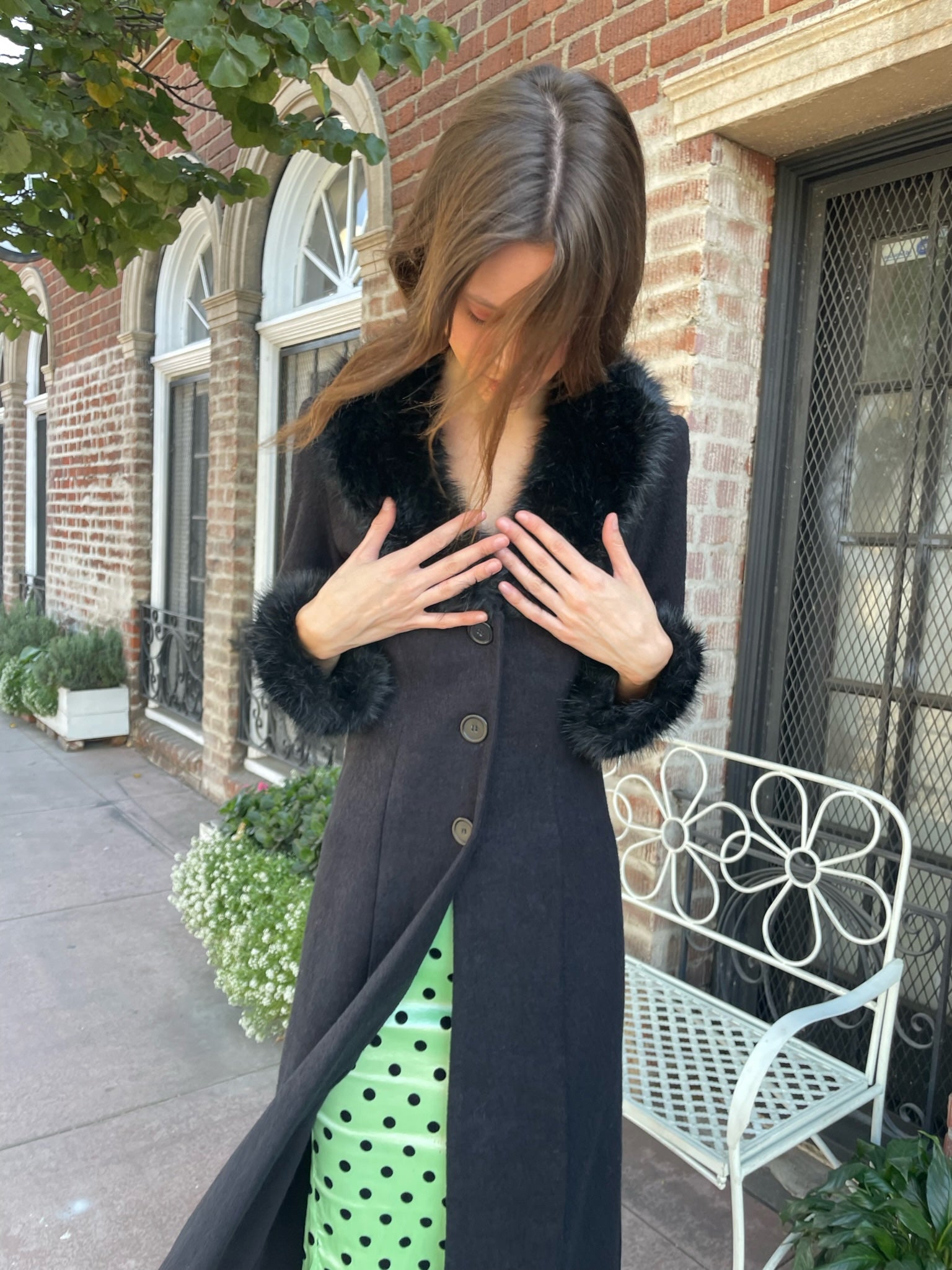 girl wearing a black fur collar coat with green polka dot dress