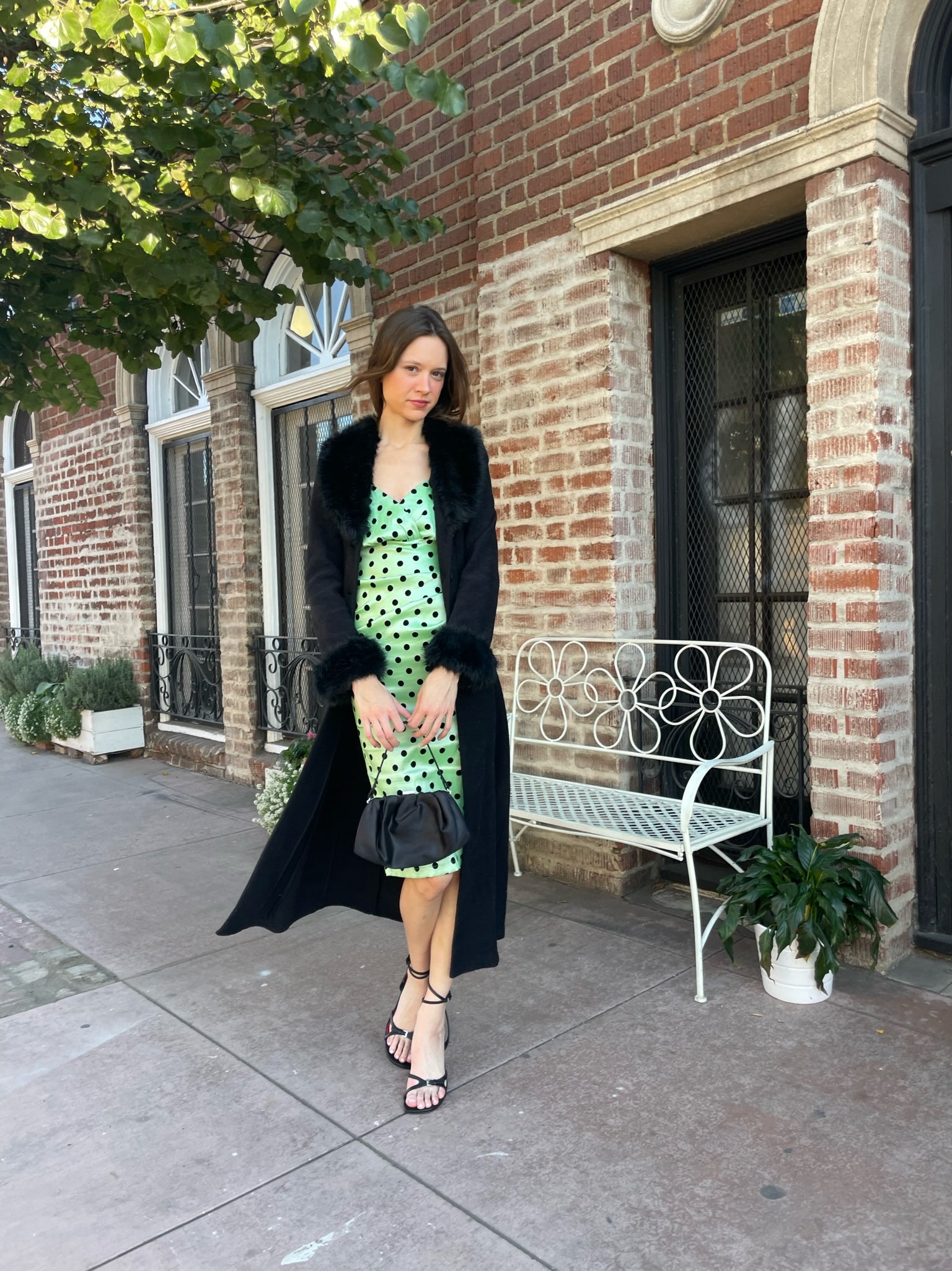 girl wearing a black fur collar coat with green polka dot dress