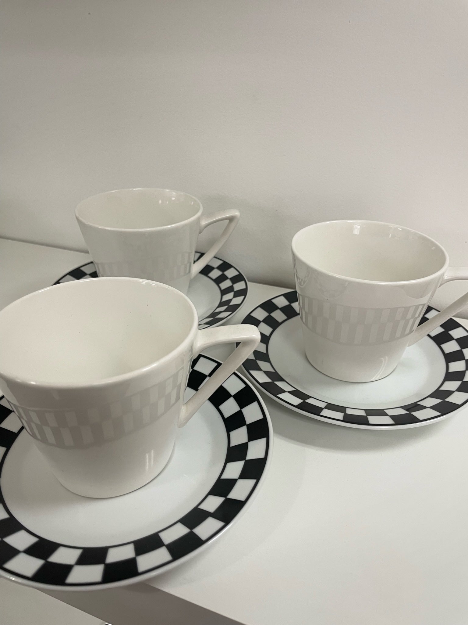 three coffee cups and saucers with black and white checker detail