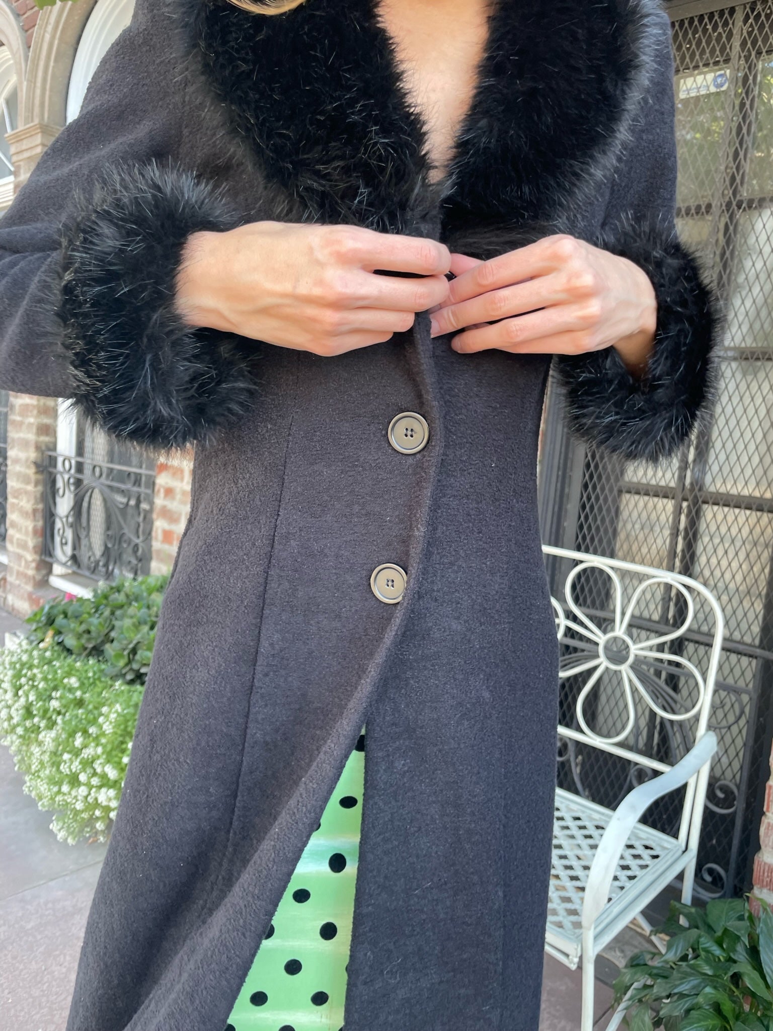 close up of girl wearing a black fur collar coat with green polka dot dress