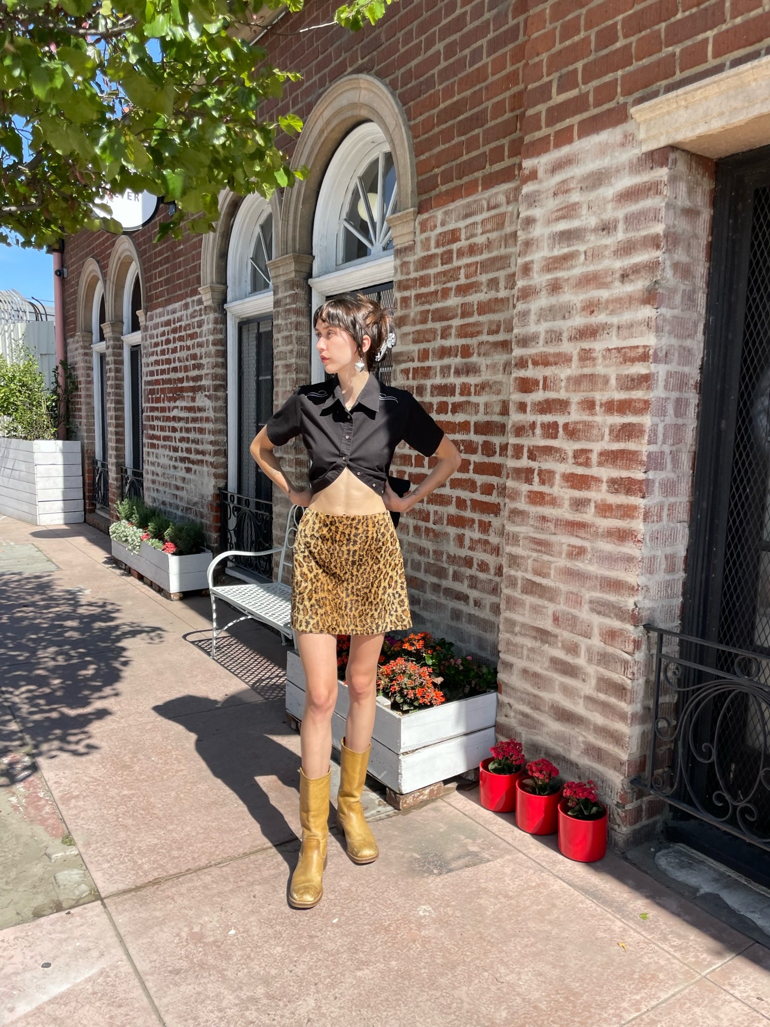 girl wearing a black button up shirt and leather mini skirt and brown boots