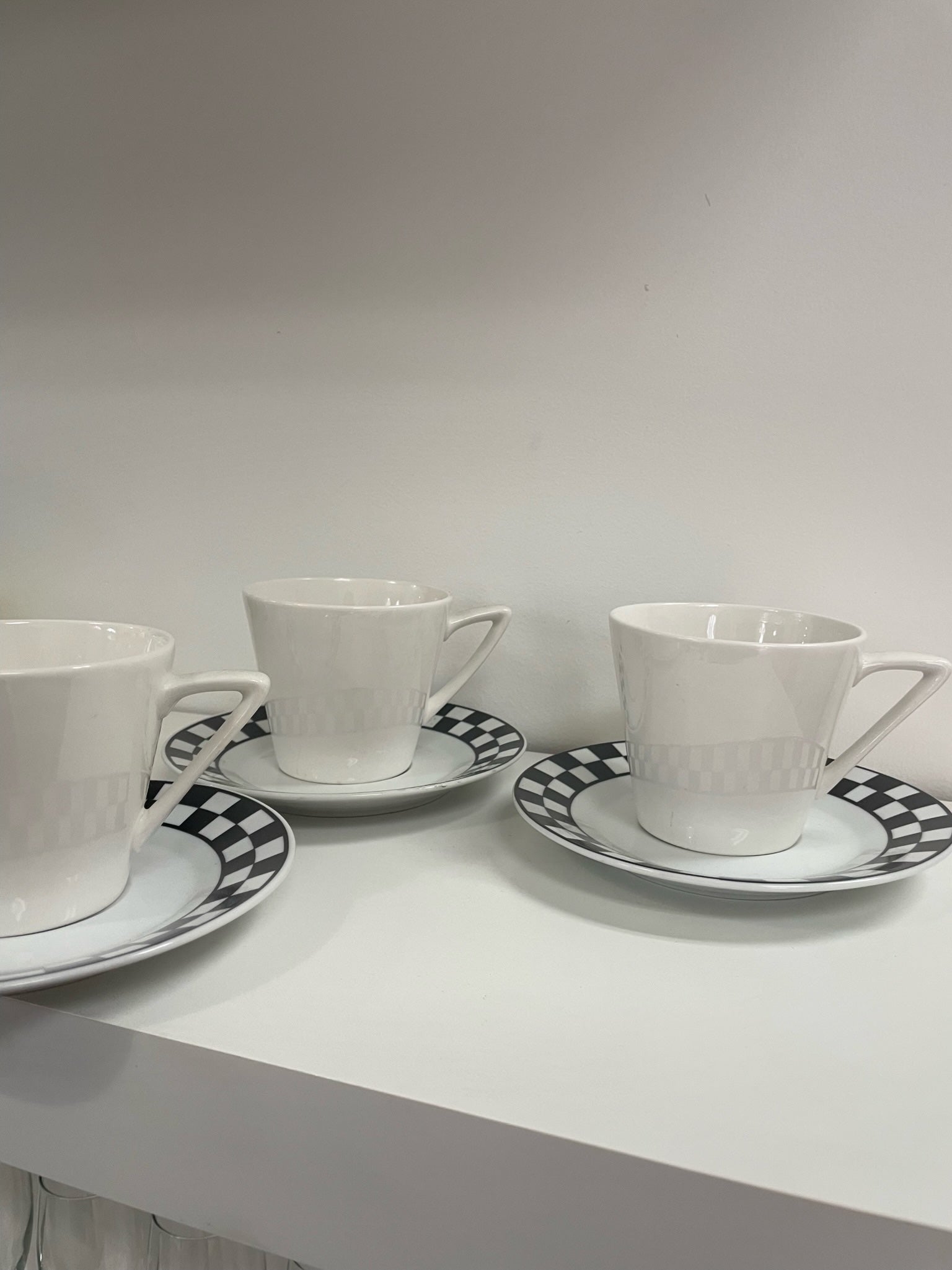 three coffee cups and saucers with black and white checker detail