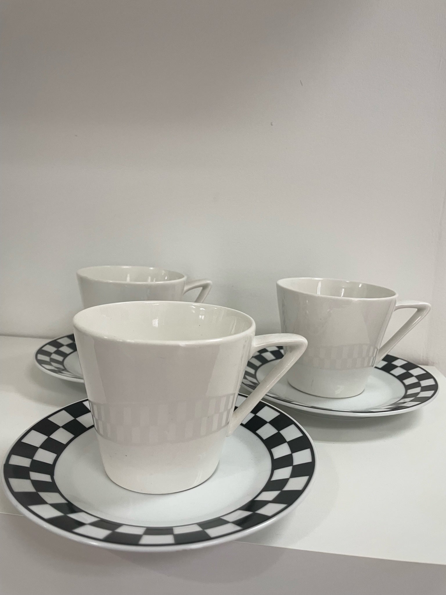 three coffee cups and saucers with black and white checker detail