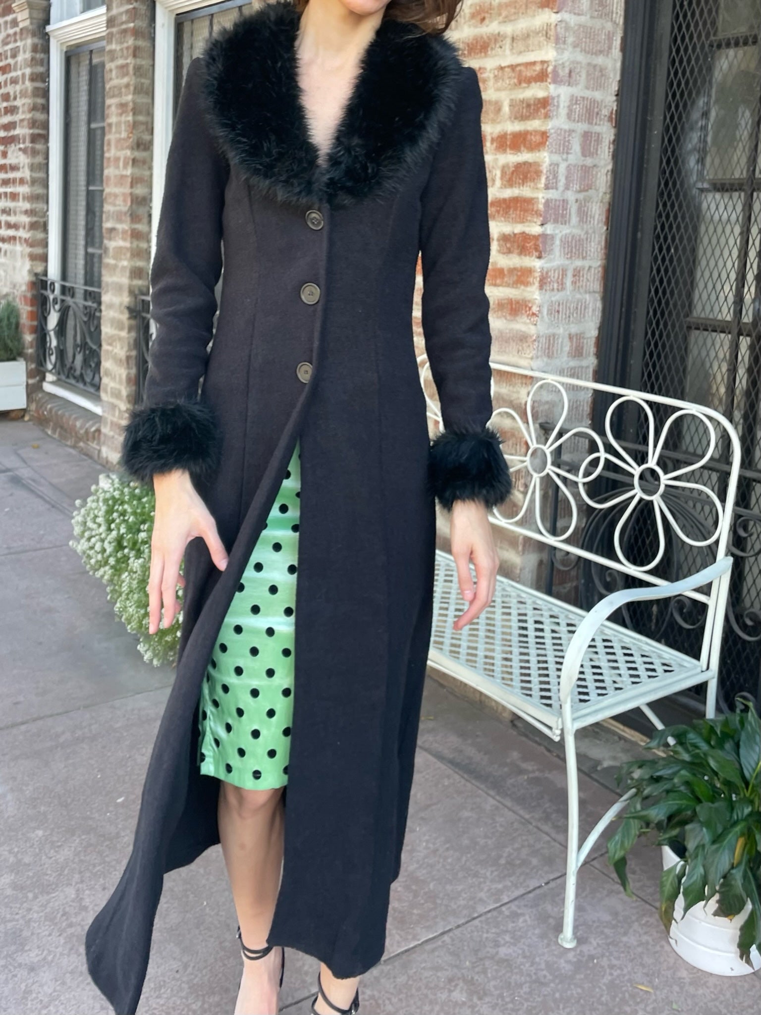 girl wearing a black fur collar coat with green polka dot dress