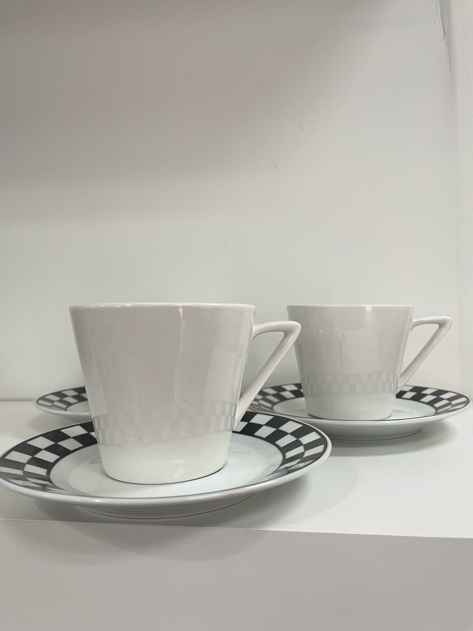 three coffee cups and saucers with black and white checker detail