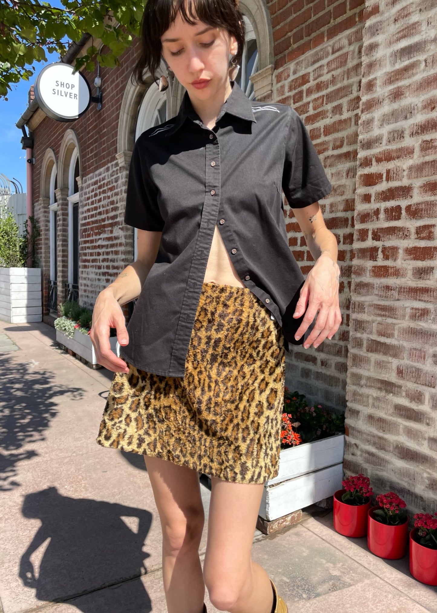 girl wearing a black button up shirt and leather mini skirt and brown boots