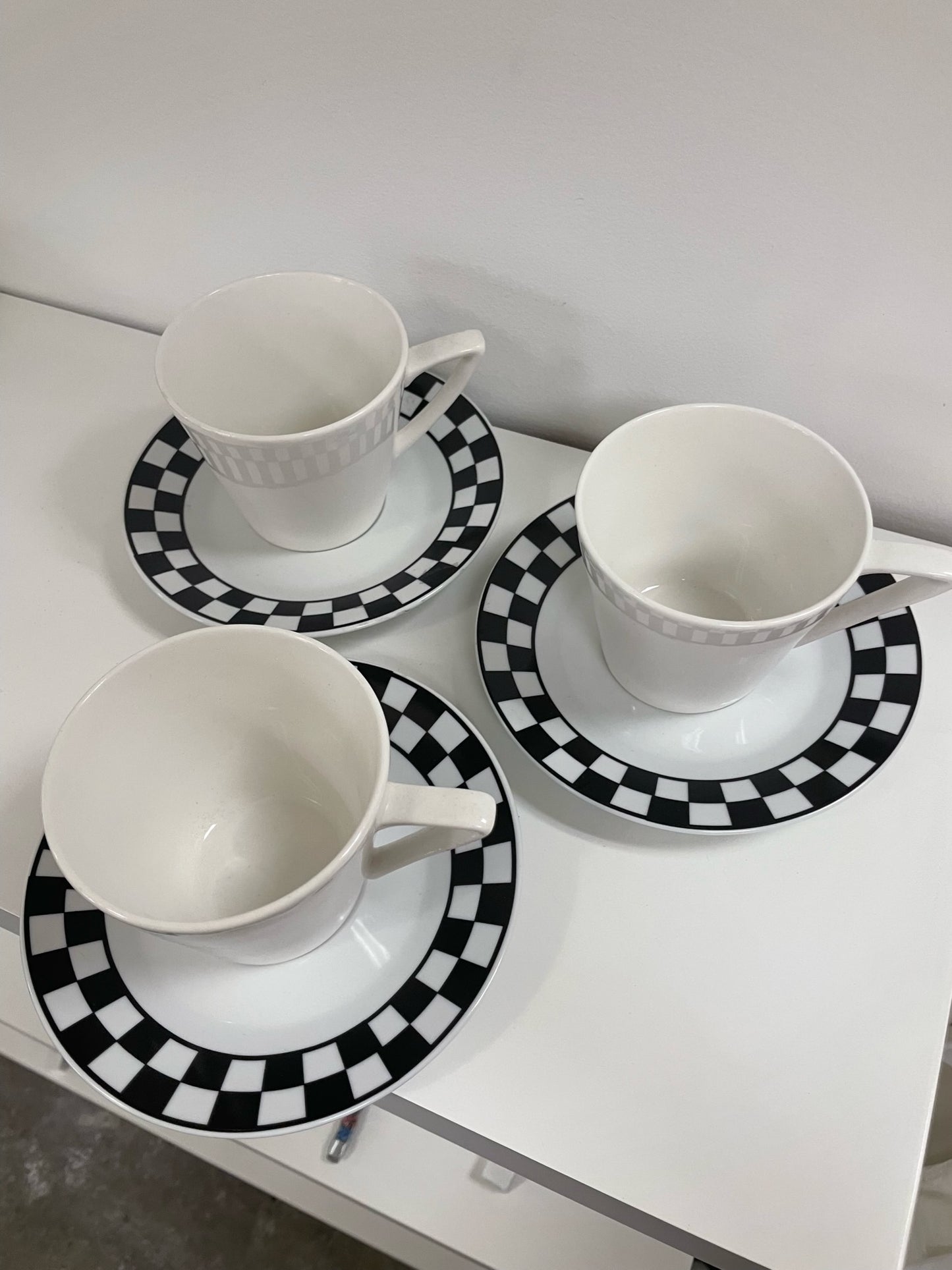 three coffee cups and saucers with black and white checker detail