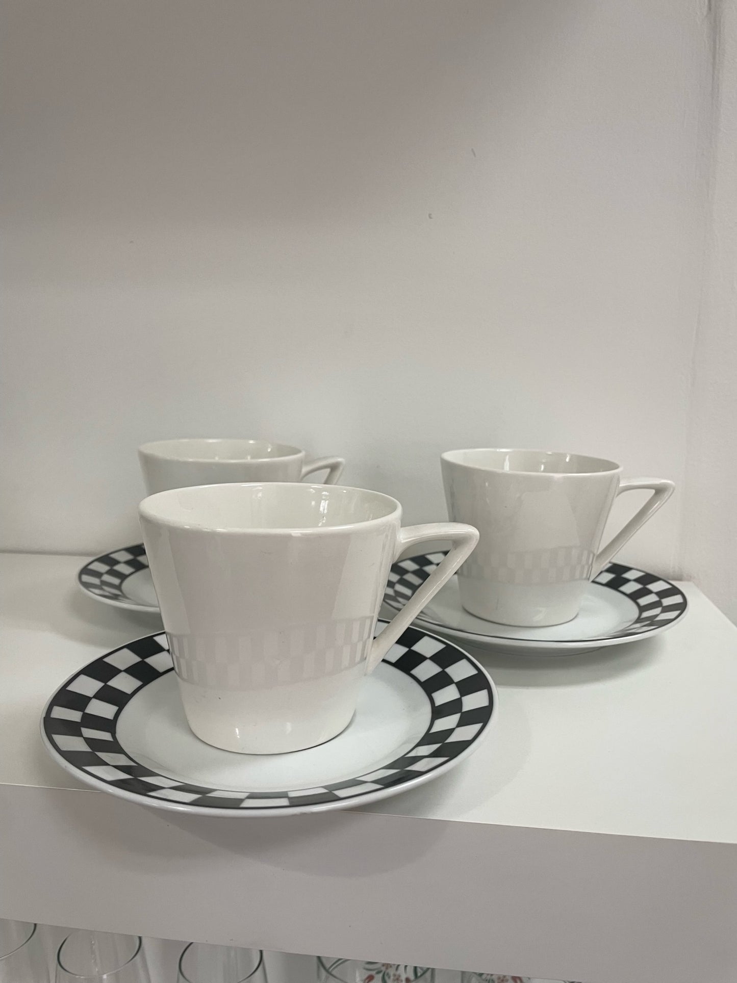 three coffee cups and saucers with black and white checker detail