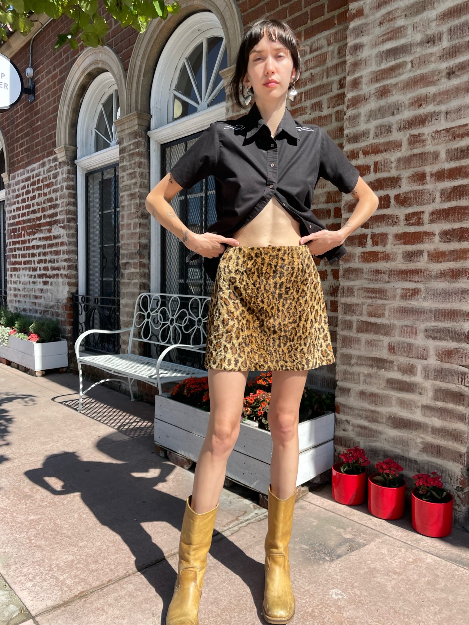 girl wearing a black button up shirt and leather mini skirt and brown boots