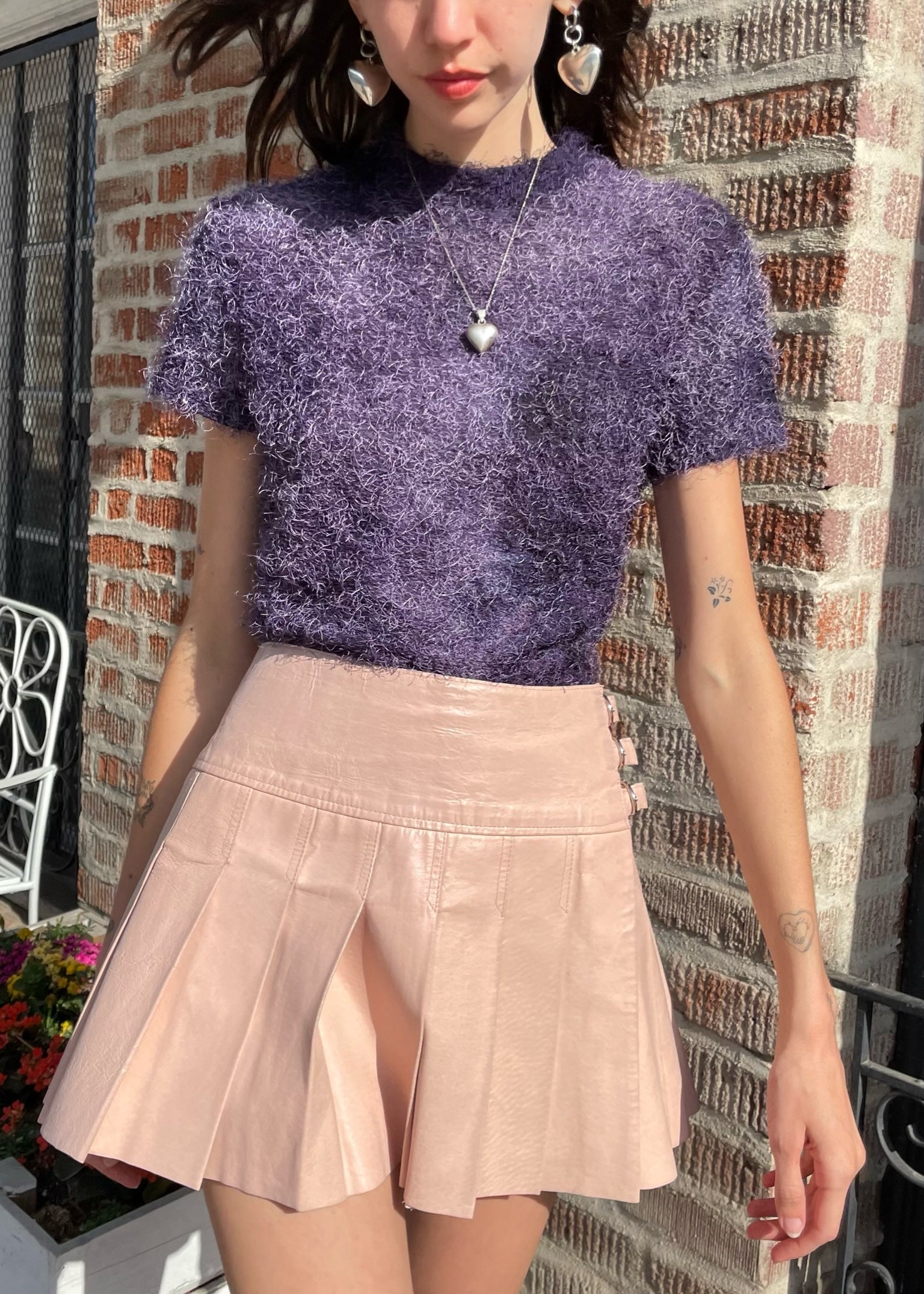 girl wearing textured purple shirt and leather pink pleated skirt