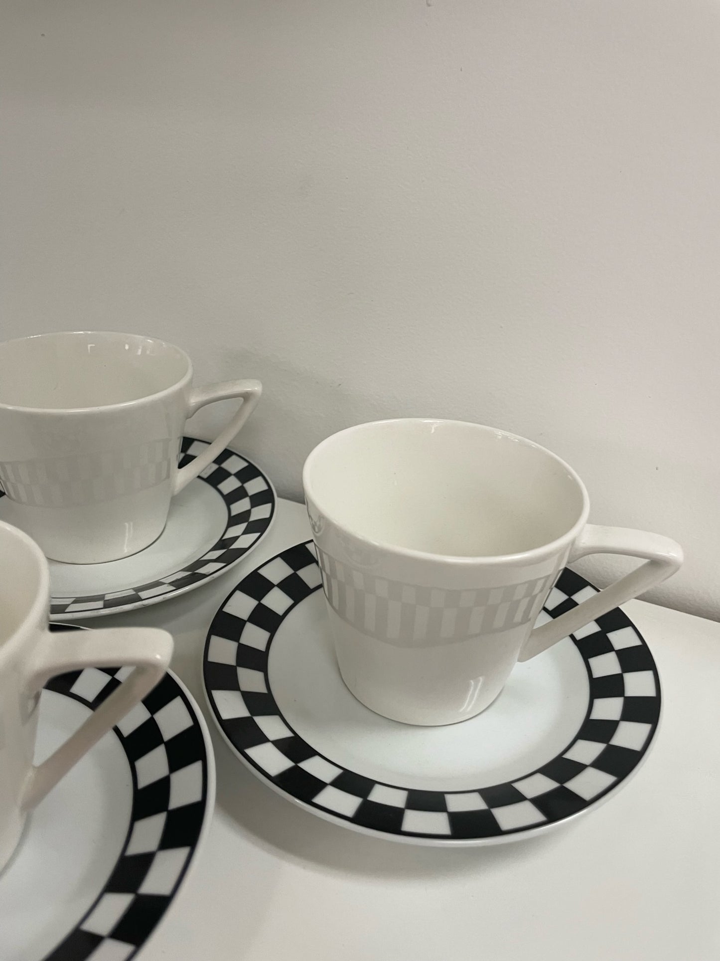 three coffee cups and saucers with black and white checker detail