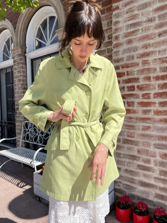 girl wearing light green pea coat and white skirt
