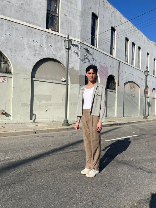 boy wearing a grey zipper jacket , brown slacks and a white tank top