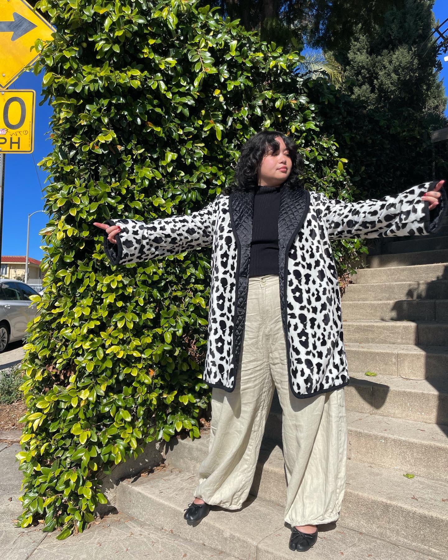 girl wearing cow print coat and white pants