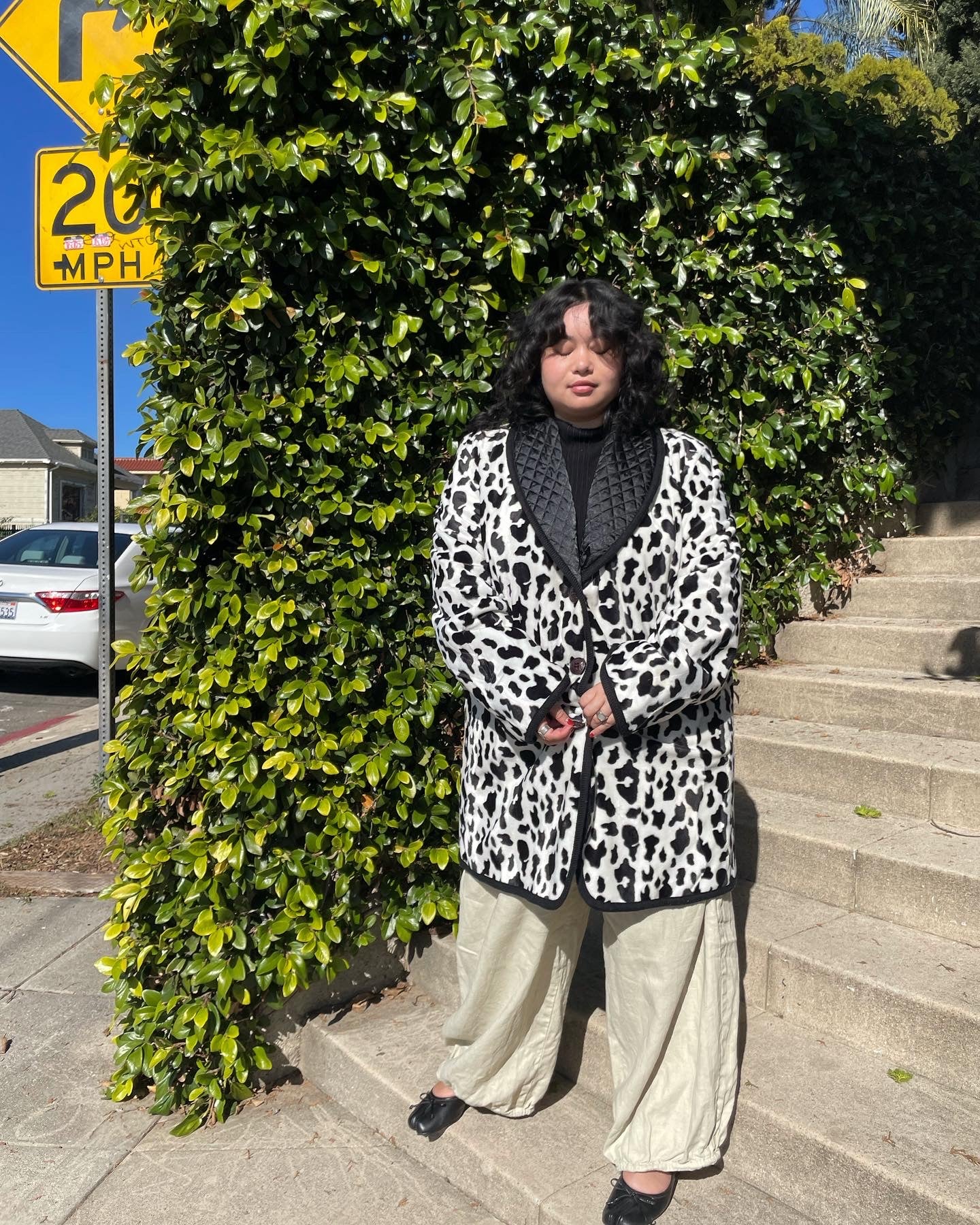 girl wearing cow print coat and white pants