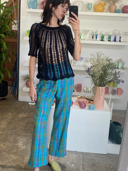 girl taking a selfie wearing black crochet top and blue flare pants