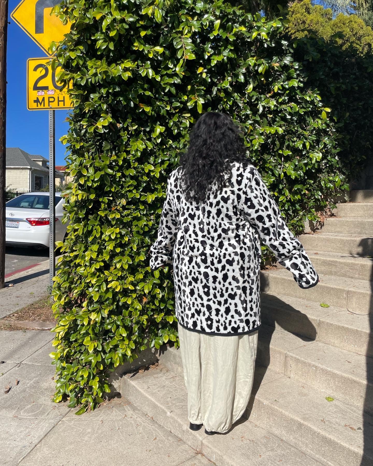 back of girl wearing cow print coat and white pants